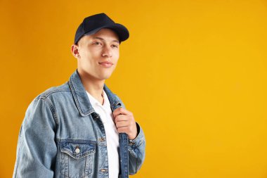 Turuncu arka planda şık beysbol şapkalı genç adam, mesaj için yer var.