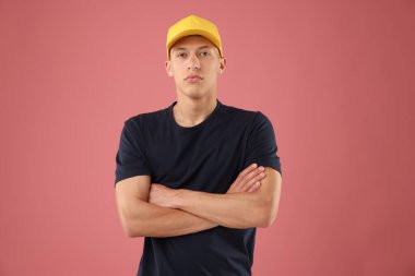 Pembe arka planda şık bir beyzbol şapkası takan genç adam.