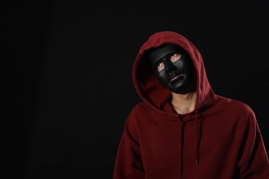 Anonimlik. Koyu arkaplanda maske takan adam, metin için boşluk