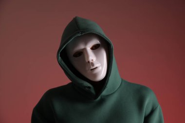 Anonimlik. Kırmızı arka planda maske takan adam