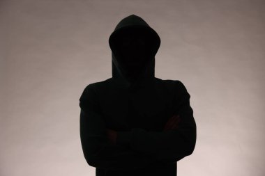 Gri arka planda kapüşonlu isimsiz bir adamın silueti.