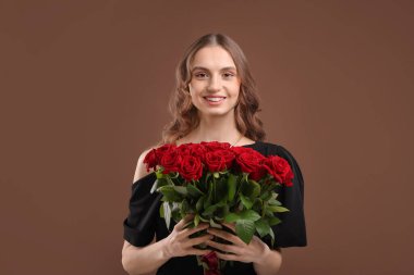 Kahverengi arka planda gül buketi olan gülümseyen kadın.