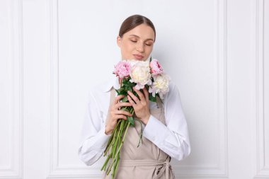 Beyaz duvarın yanında güzel şakayık demeti olan bir çiçekçi.