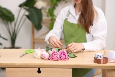 Çiçekçinin ahşap masasında şakayık buketi yapan çiçekçi, yakın plan. Metin için boşluk