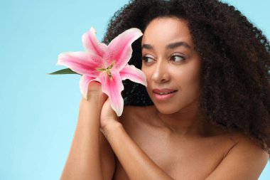 Açık mavi arkaplanda spa tedavisinden sonra çiçekli güzel Brezilyalı kadın portresi, yakın plan.