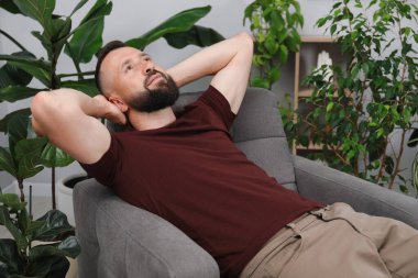 Uyum. Evdeki rahat koltukta dinlenen adam.