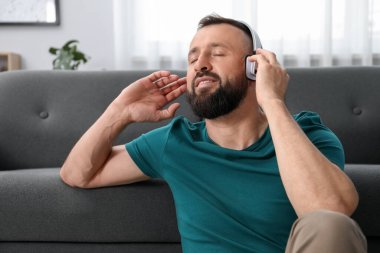 Uyum. Evde kulaklıkla müzik dinleyen bir adam.