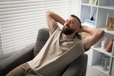 Uyum. Evdeki rahat koltukta dinlenen adam.