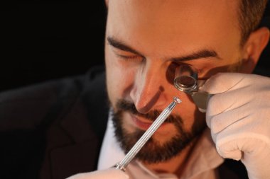 Kapalı alanda lüks mücevher değerlendirmesi yapan loupe 'a değer biçen bir eksper.