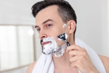 Yakışıklı bir adam evde tıraş olurken, yakın plan.