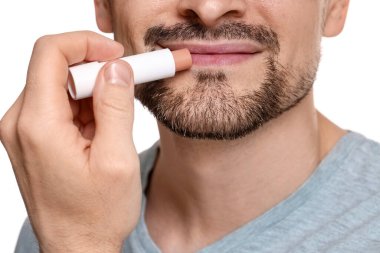 Beyaz arka planda dudaklarına dudak kremi süren adam, yakın plan.
