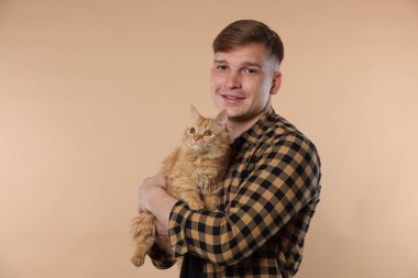 Bej arka planda sevimli kızıl kedisi olan adam.