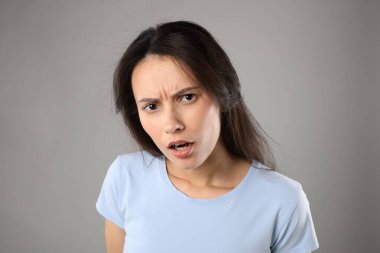 Gri arka planda kafası karışmış kadın portresi