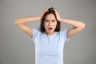 Gri arka planda şok olmuş bir kadının portresi