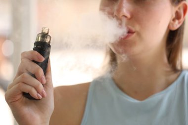 Dışarıda elektronik sigara içen genç bir kadın, yakın plan.