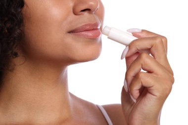 Beyaz arka planda dudaklarına dudak kremi süren kadın, yakın plan.