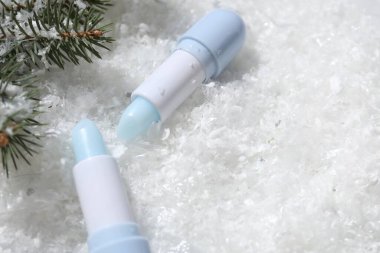 Nemlendirici dudak merhemi ve yapay kar üzerinde köknar ağacı dalları, yakın plan. Metin için boşluk