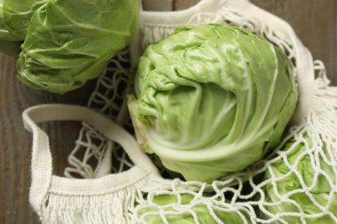 Taze lahanalar ve ahşap masada ağ torba, yakın plan.