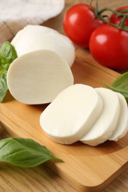 Lezzetli mozzarella, domates ve fesleğen ahşap masada, yakın plan.