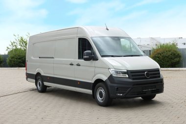 Asfalt yolda park etmiş beyaz bir minibüs.