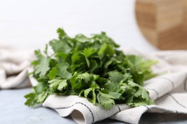 Açık gri masada taze aromatik kişniş ve havlu, yakın plan.