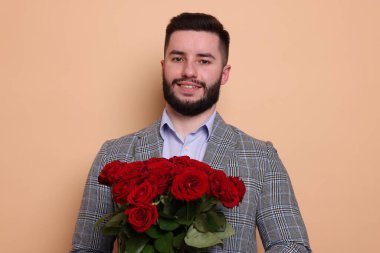 Bej arka planda kırmızı gül buketi olan mutlu adam.