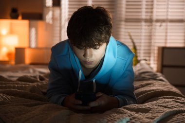 Ergen çocuk evde akıllı telefon kullanıyor.