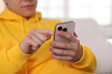 Ergen çocuk evde akıllı telefon kullanıyor, yakın plan.