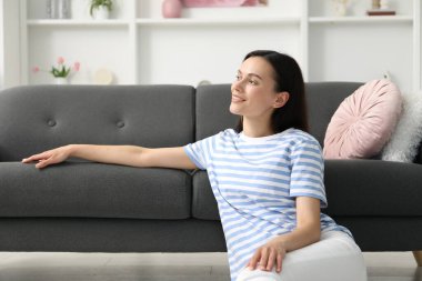 Uyum. Gülümseyen kadın evdeki kanepede uzanırken dinleniyor.