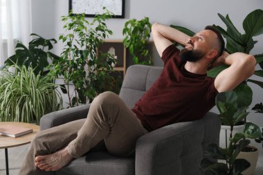 Uyum. Evdeki rahat koltukta dinlenen adam.