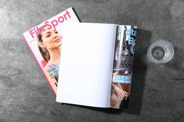 Moda dergileri ve gri arka planda bir bardak su, üst manzara. Tasarım için model