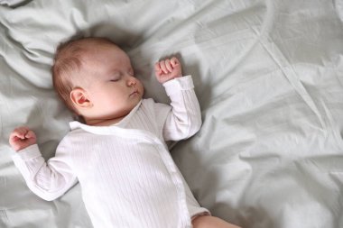 Yeni doğmuş şirin bir bebek yatakta uyuyor, manzarası çok güzel. Metin için boşluk