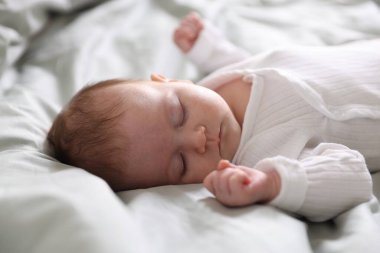 Sevimli yeni doğmuş bebek yatakta uyuyor, yakın plan.