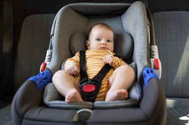 Bebek koltuğuna bağlanmış şirin bir bebek.