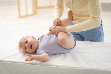 Anne, sevimli bebeğiyle evde masasını değiştirip oynuyor.