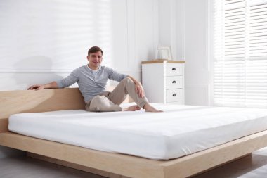 Evdeki yumuşak yatakla yatakta oturan genç adam, mesaj için yer var.