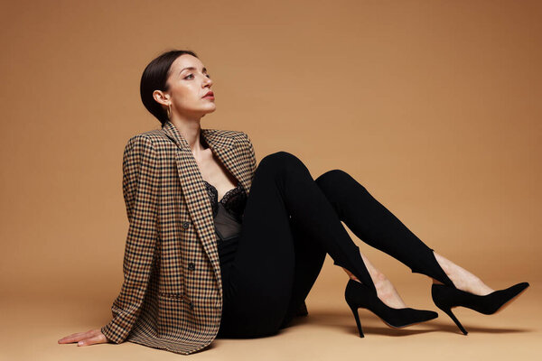 Полнометражный портрет красивой женщины в стильном наряде на бежевом фоне