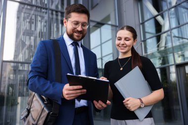 Mutlu iş arkadaşları ofis binasının yakınında düşük açılı bir şeyler tartışıyor.