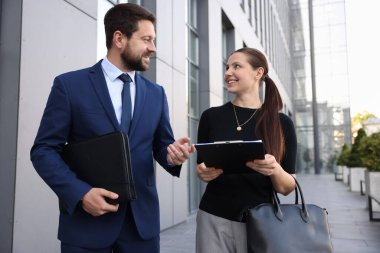 Mutlu iş arkadaşları ofis binasının yakınında bir şeyler tartışıyor.