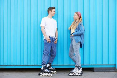 Açık mavi duvarın yanında patenli mutlu çift