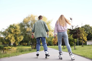 Çiftler yaz günü parkta birlikte paten kayıyorlar.