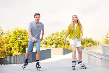 Mutlu çift sokakta birlikte paten kayıyor.