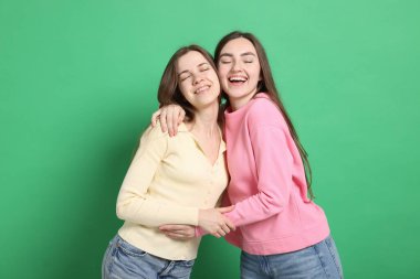 Mutlu arkadaşlar yeşil arka planda birbirlerine sarılıyorlar.