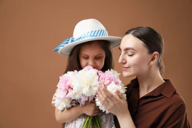 Anne ve kızı kahverengi arka planda bir buket güzel şakayıkla mesajlaşmak için yer açıyorlar.