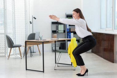 Ofiste masa başında egzersiz yapan güzel bir kadın.