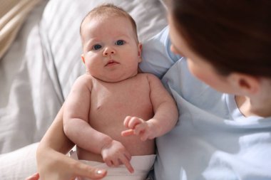 Anne, yeni doğmuş bebeğini evde uyuması için yatırıyor.