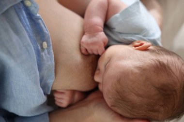 Anne yeni doğmuş bebeğini evin içinde emziriyor.