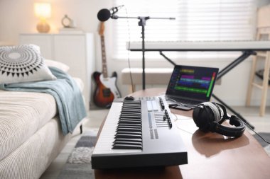 MIDI klavye, dizüstü bilgisayar ve kulaklıklar ev stüdyolarındaki ahşap masada.
