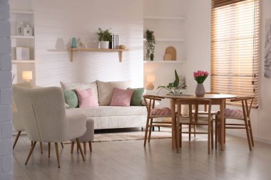 Odada rahat bir kanepe ve sandalyeli şık bir yemek masası. İç tasarım