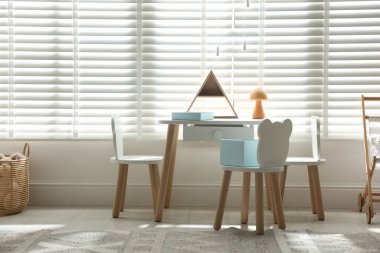 Şık oyun odasında küçük masa, sandalye ve dekor. İç tasarım